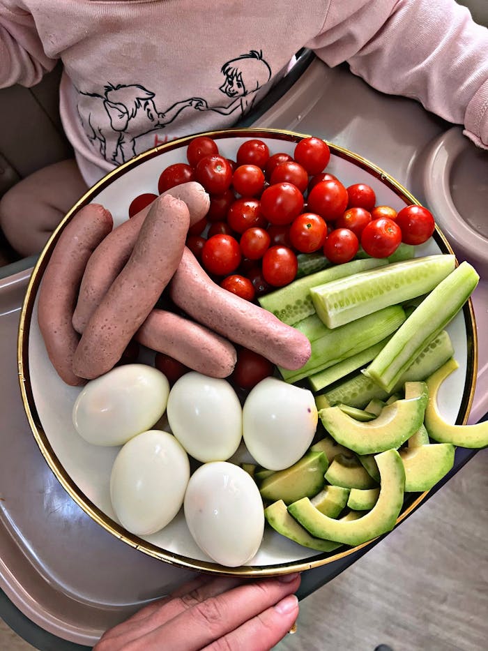 Colorful platter with fresh vegetables, eggs, and sausages, perfect for a healthy meal.